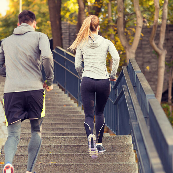 couple-running-upstairs-in-city-park-PWB2HKX-lowres